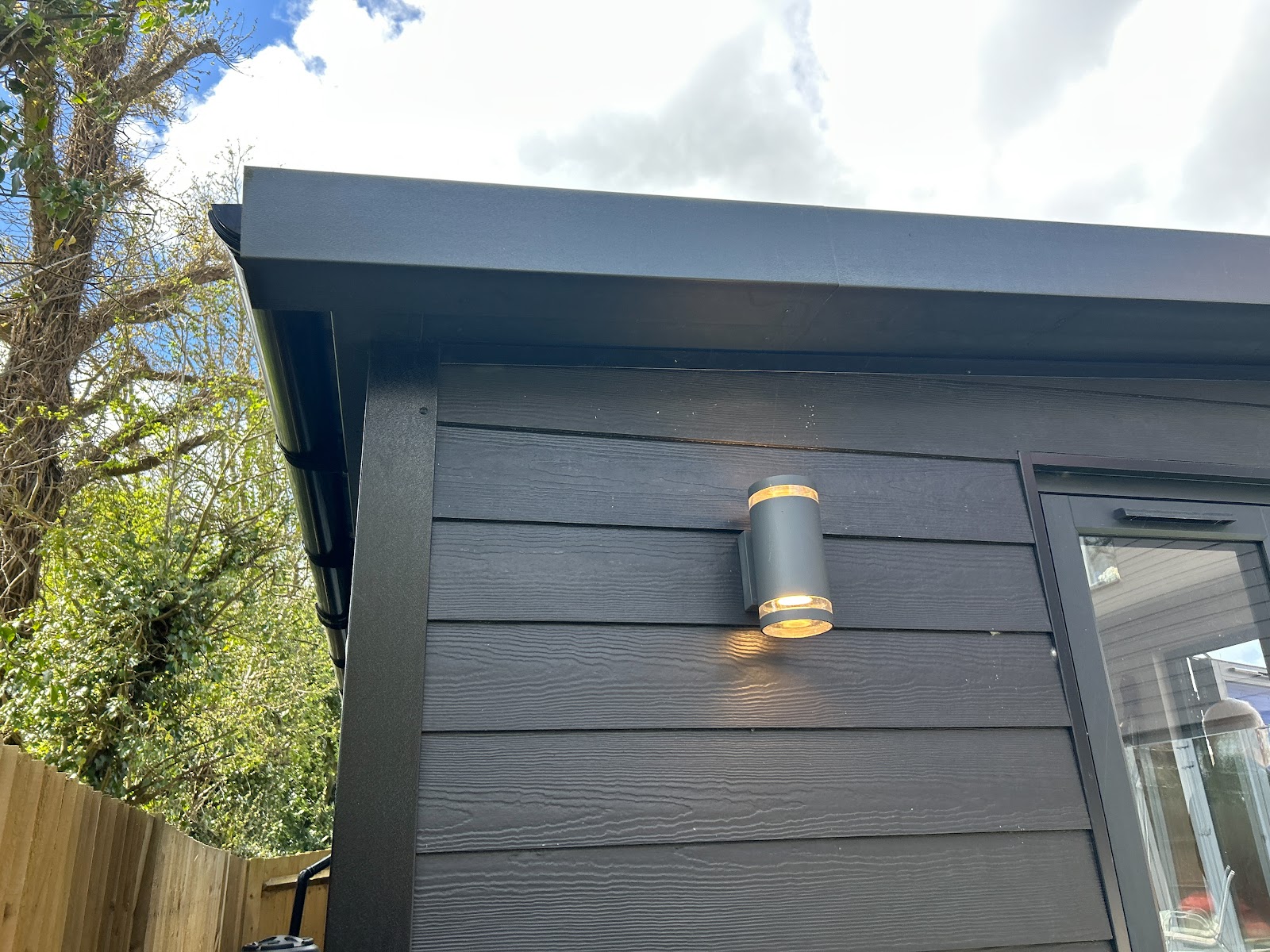 Roofline, fascia and a wall-mounted downlight on composite cladding — the trim details that mark a proper build.